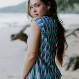 Handmade Firozi Ikat top in shades of blue, worn by a woman on a beach, showcasing ethical fashion crafted from lightweight cotton fabric