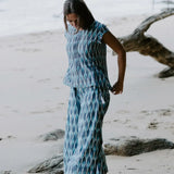 Sustainable fashion blue Ikat top on a woman by the shore, crafted by artisans with traditional Indian weaving techniques