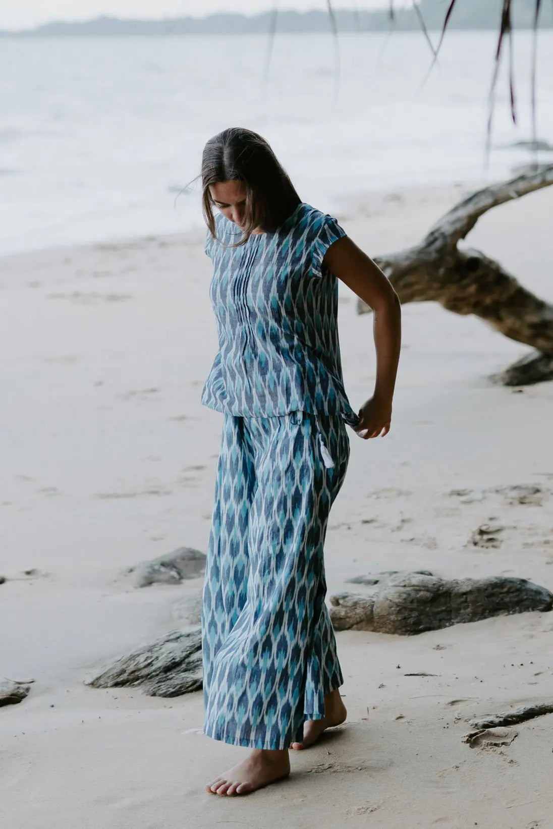 Sustainable fashion blue Ikat top on a woman by the shore, crafted by artisans with traditional Indian weaving techniques